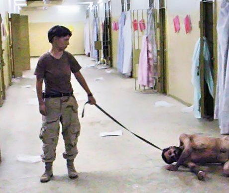 Photo of soldier holding leashed prisoner at Abu Ghraib